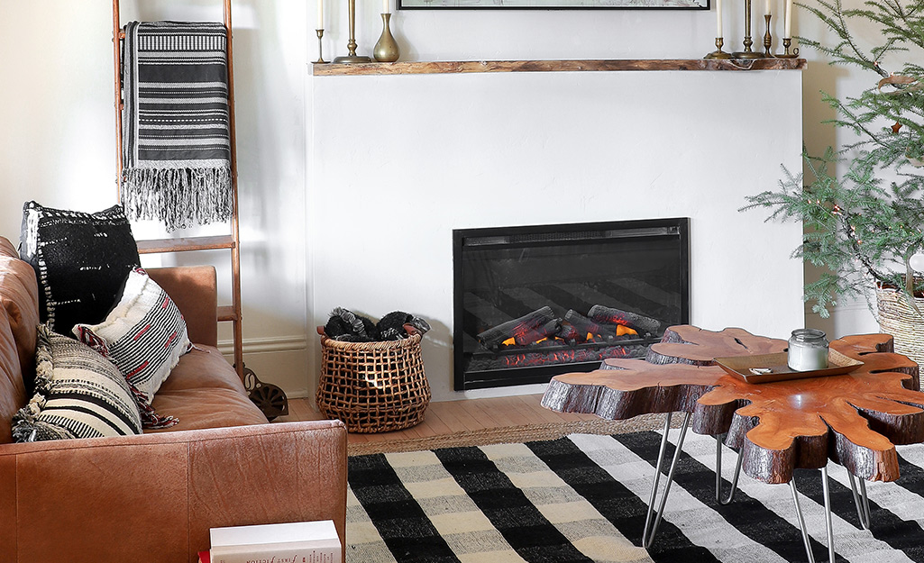 A leaf-shaped coffee table stands on a black and white rug in front of a lit fireplace with a modern white facade.