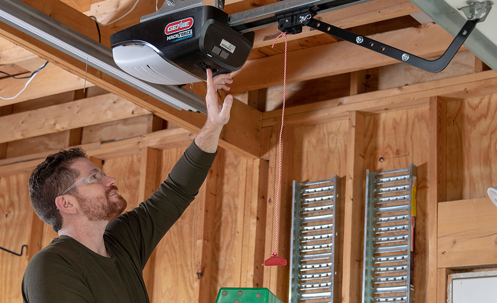 A person sets a garage door opener after installation.