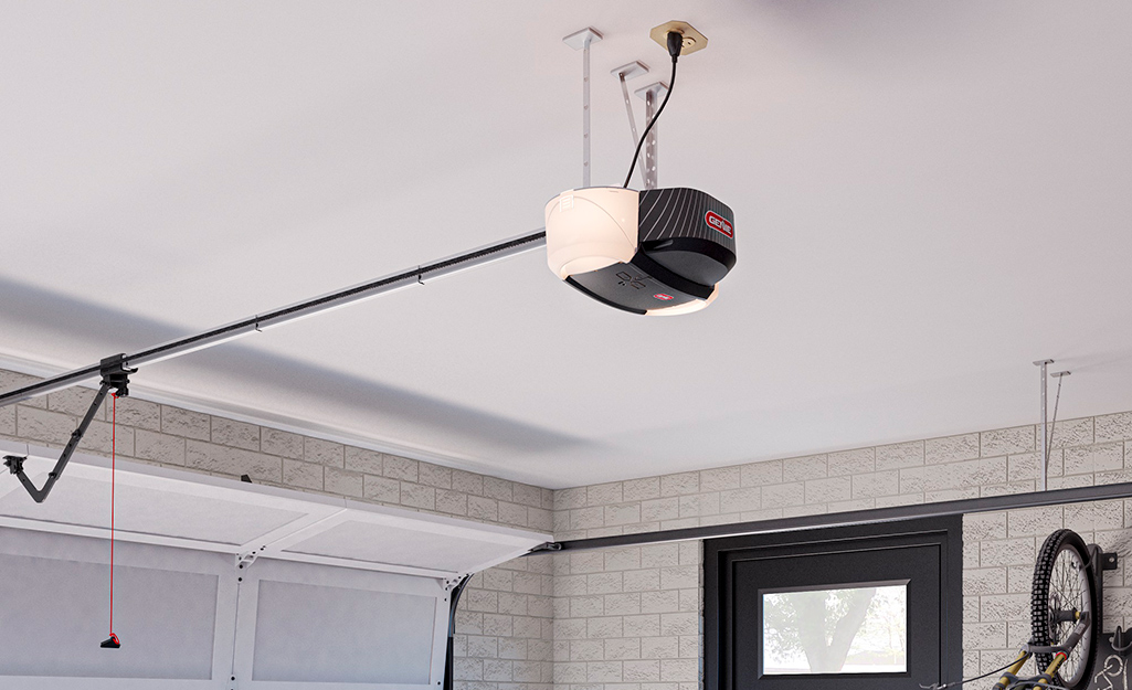 A belt drive garage door opener hangs from a ceiling.
