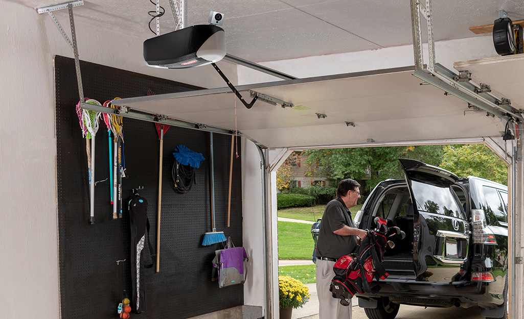A screw drive garage door opener hangs from a ceiling.