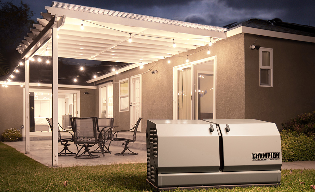 A home standby generator beside a patio lit by string lights.