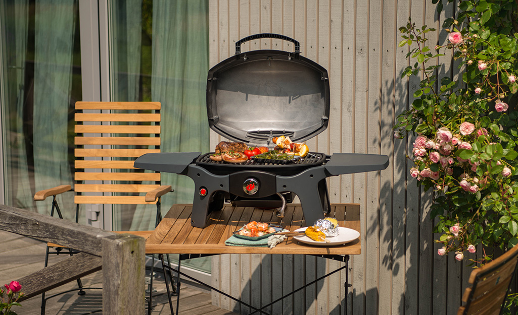 A portable grill sitting on a table on a patio.