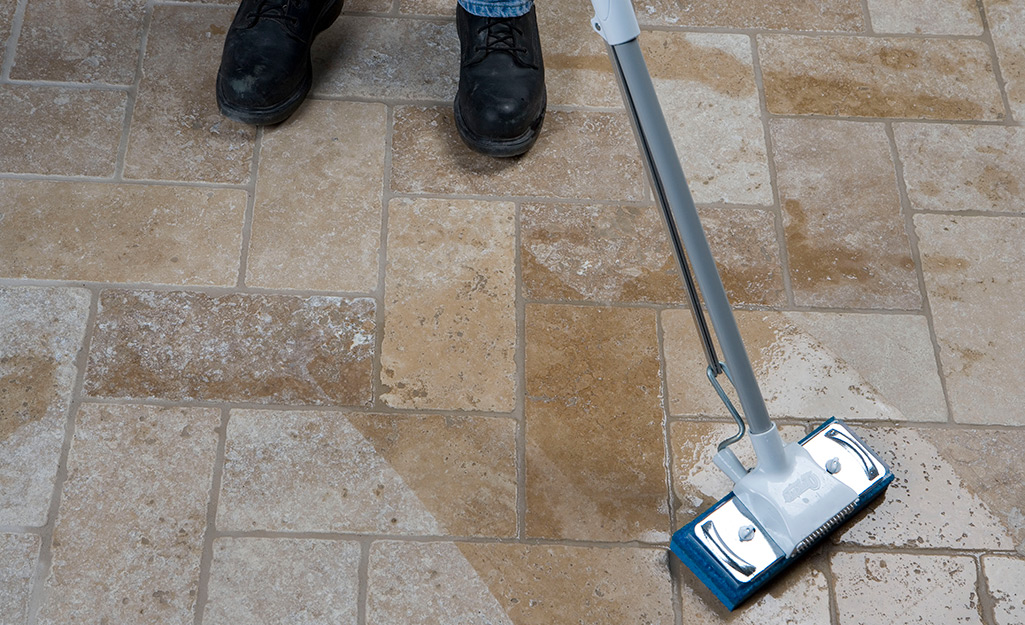 Someone sealing floor tiles with a sponge mop.