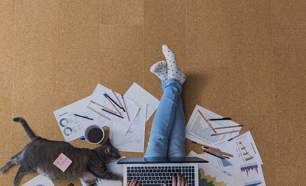 A person works while sitting in a room with cork flooring.