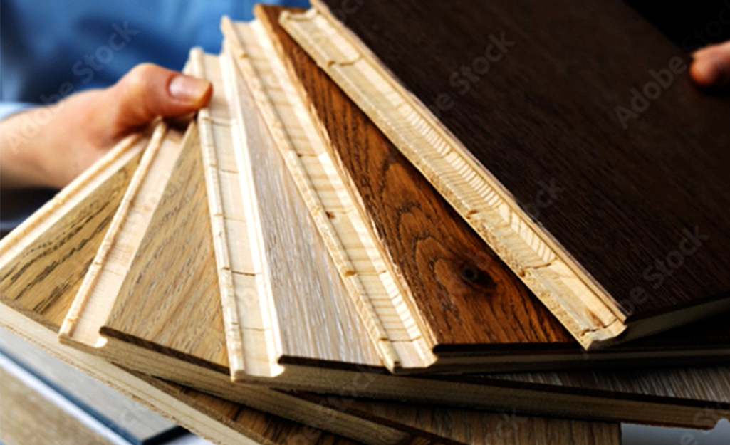 A person holds samples of hardwood flooring with different edge styles.