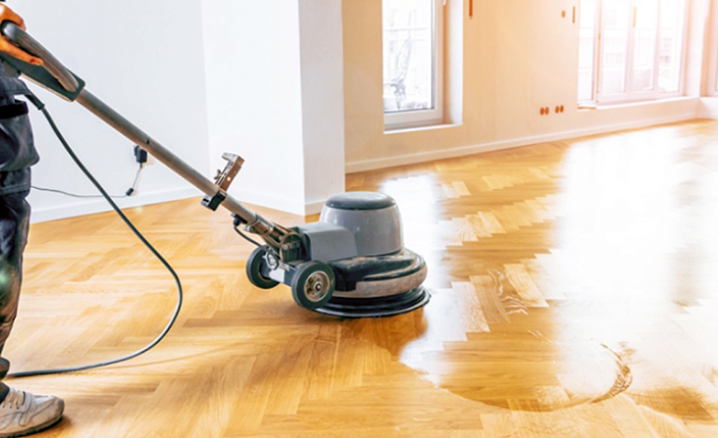 A worker applies waterproofing sealant to a hardwood floor. 