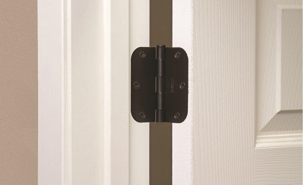 A butt hinge attached to a door and frame.