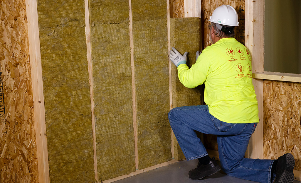 A person installs wall insulation.