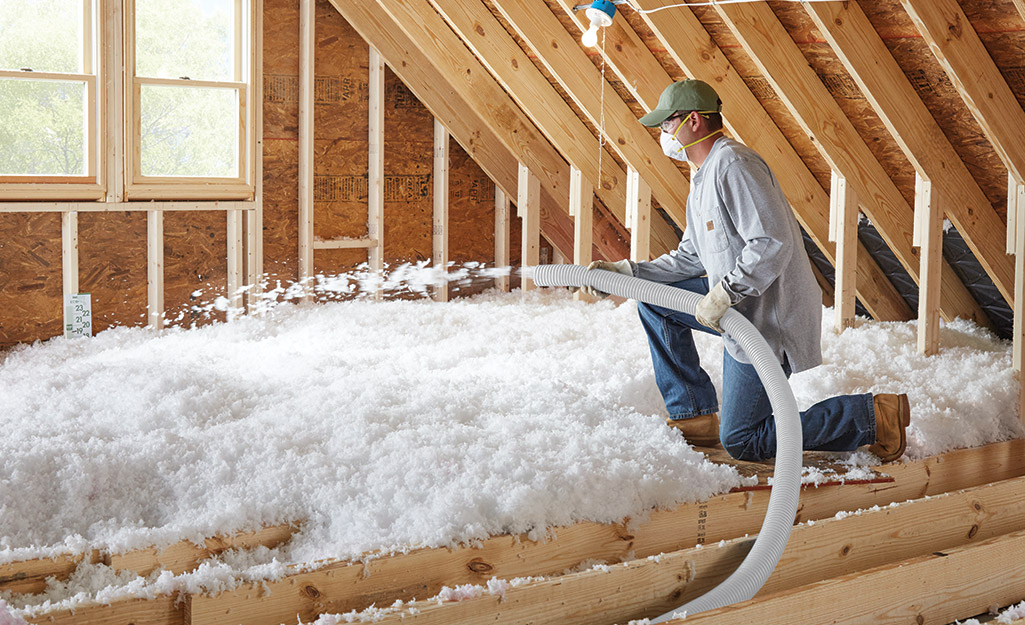 A person spraying loose fill insulation.