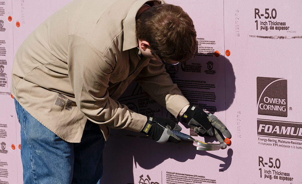 A person installing foam board insulation.