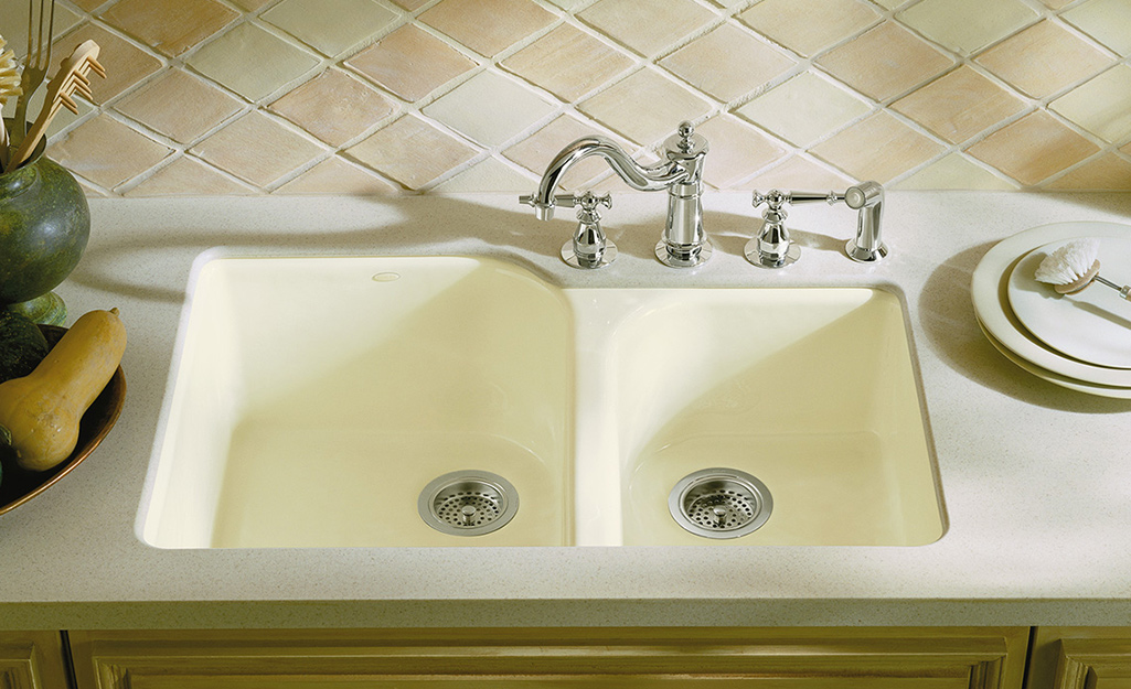 A double bowl sink with four tappings for a faucet, sprayer and soap dispenser.