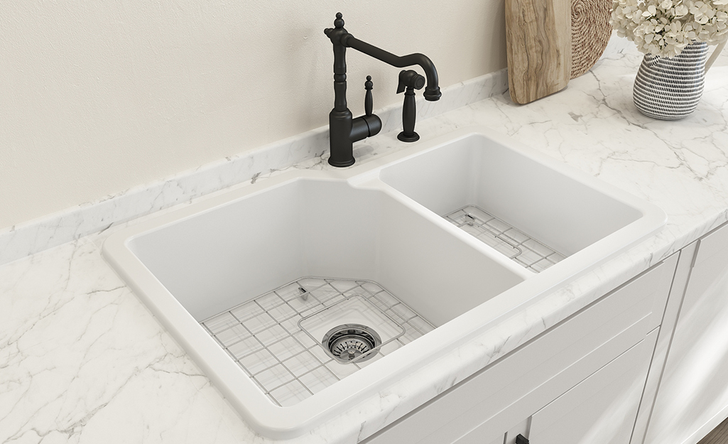 A top mount double-bowl kitchen sink in a white countertop.