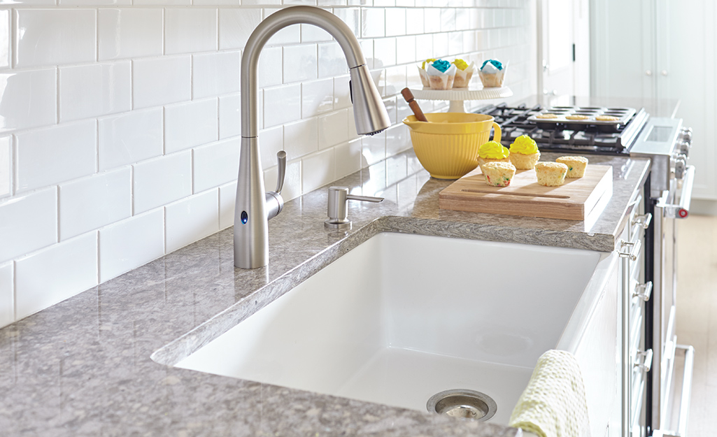 A farmhouse sink with a tall curved faucet.