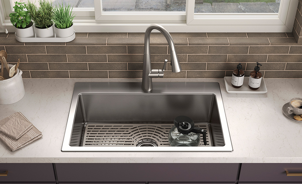 An all-in-one stainless steel kitchen sink with a pull-down faucet on a white countertop.