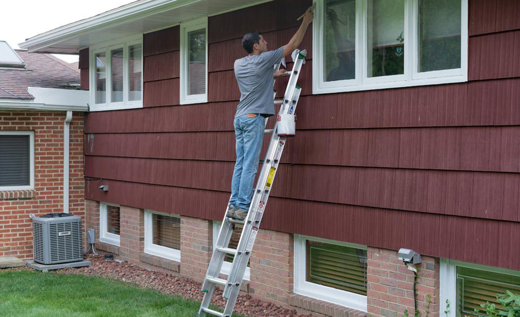 A man on an extension ladder leaned up against a house.