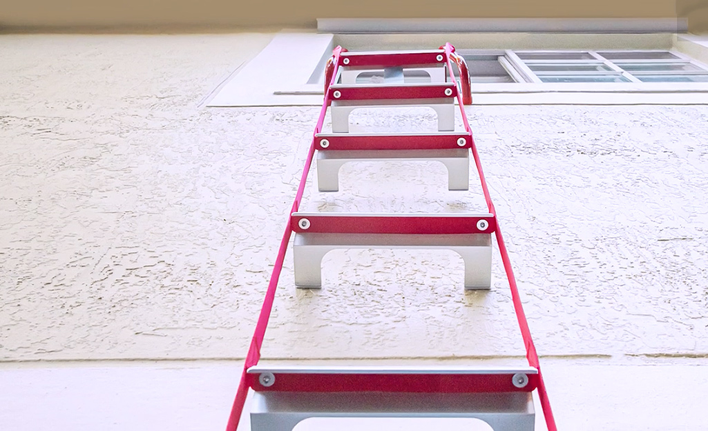 A fire escape ladder hanging from a second story window.