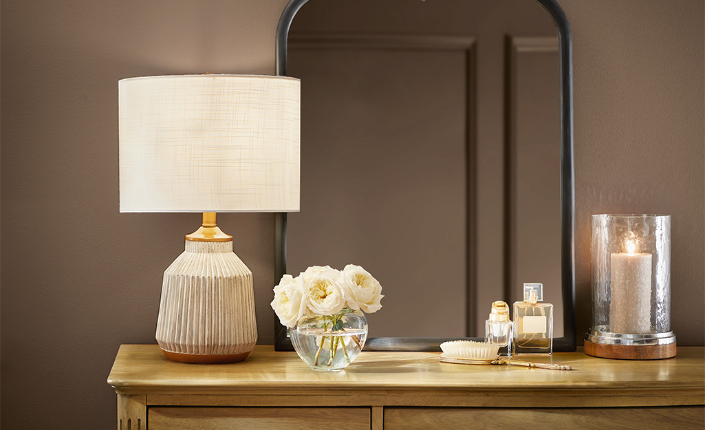 A table lamp with a round shade sitting on a buffet..