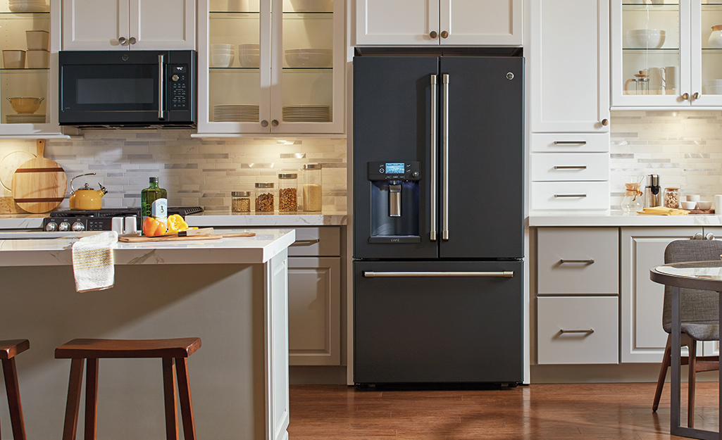 A black microwave in a kitchen with a matching refrigerator.
