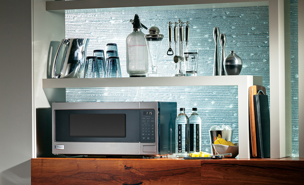 A countertop microwave in front of a glass backsplash.