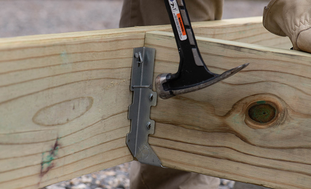 Someone using a galvanized strong-tie fastener into a metal corner brace..