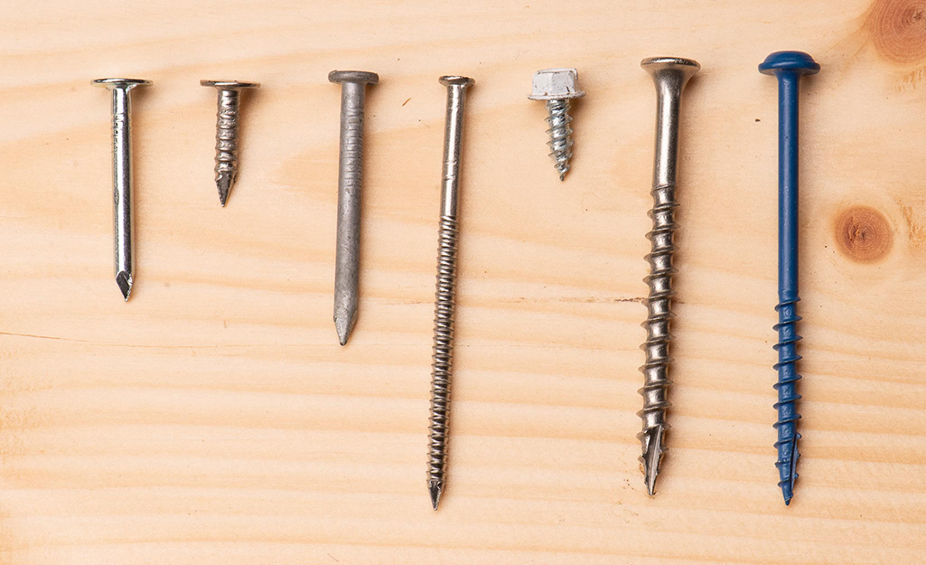 Outdoor nails and screws lined up on a wood board.