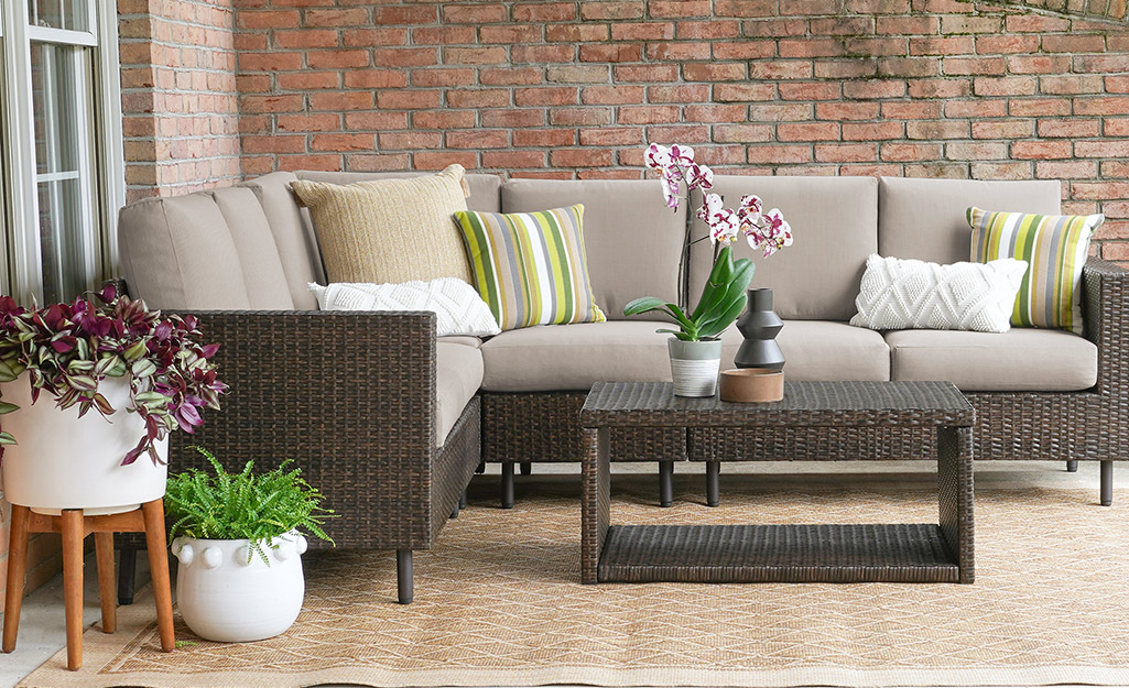 Plants grow in a containers on a patio with a sectional sofa.