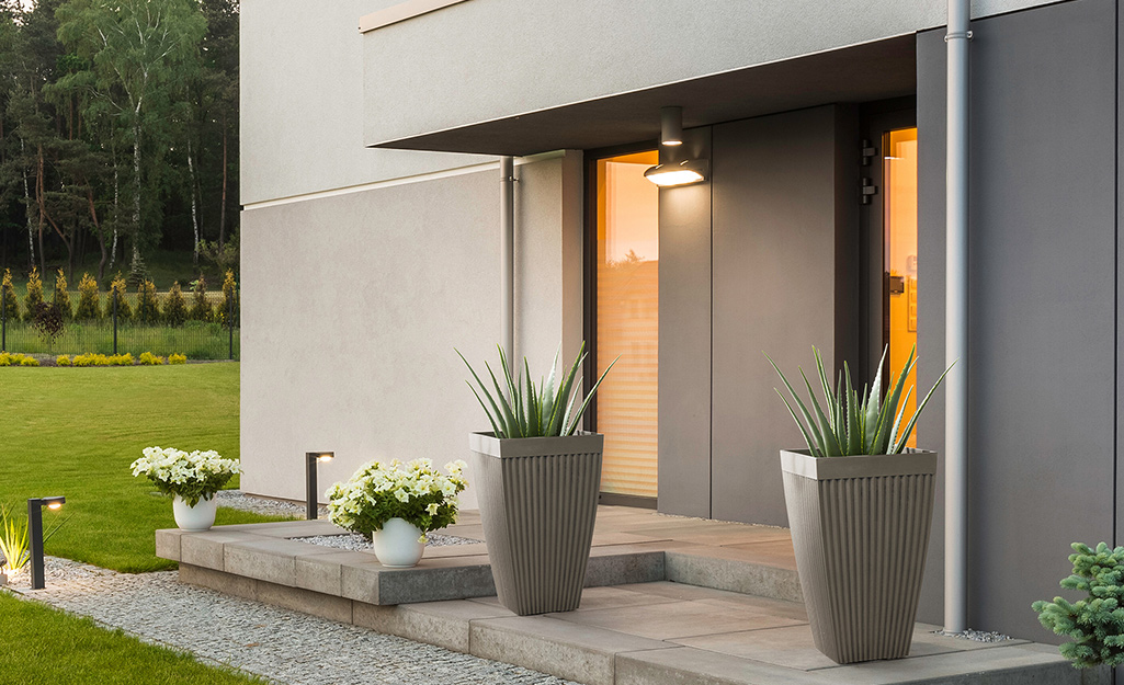 Several planters sits on a the patio of a modern style home.