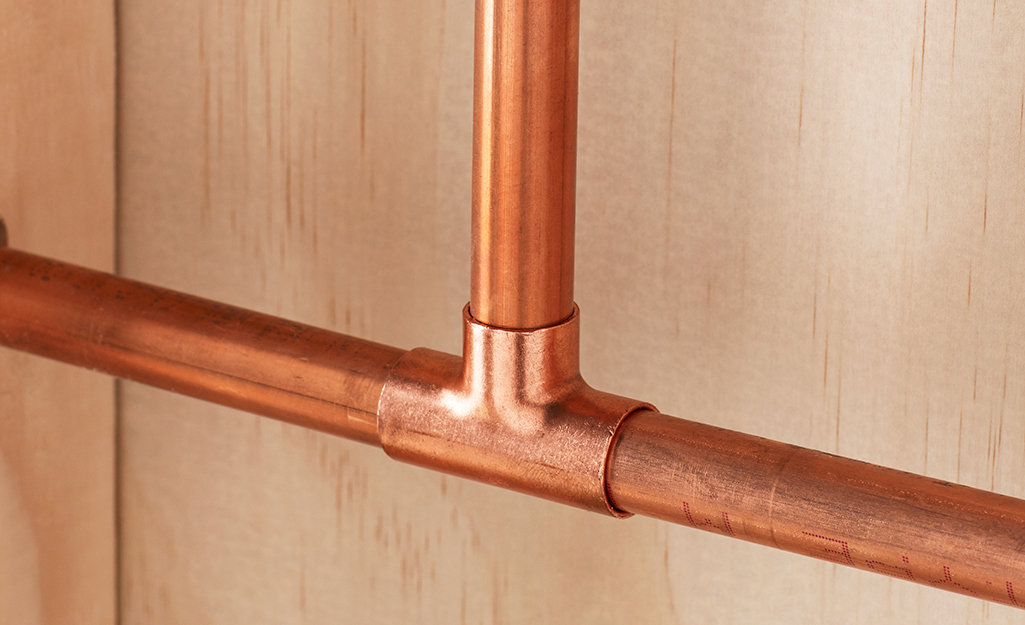 Three sections of copper pipe are connected with a pipe fitting.