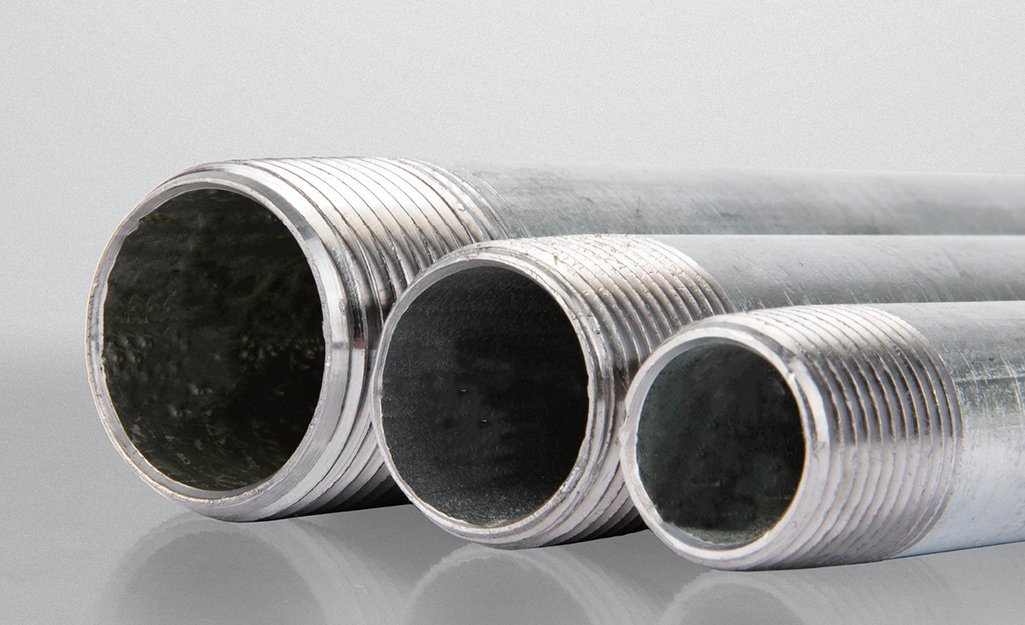Three sizes of galvanized pipes sit next to each other. 