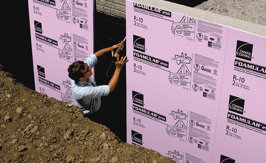 A man installs foamboard to a wall.