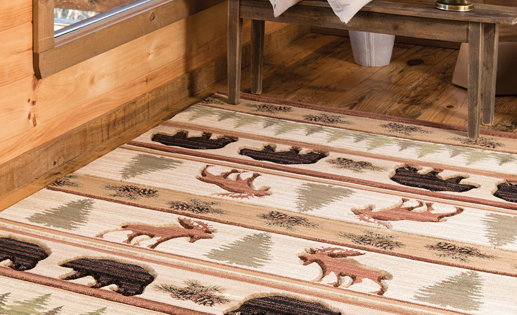 A lodge rug features bears, moose and evergreen trees.