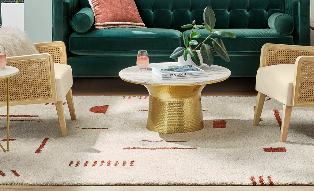 A shag rug lays under two chairs and a coffee table with a gold base.