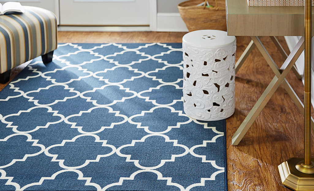 A blue and white trellis rug lays on the floor in a living room.