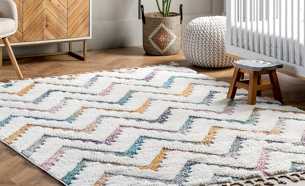 A rug with chevrons of different colors lays on a wood floor.