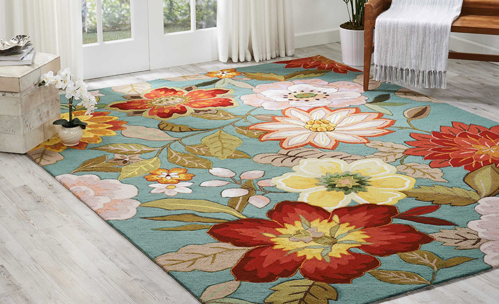 A floral rug with a pattern of large flowers lays in front of French doors.