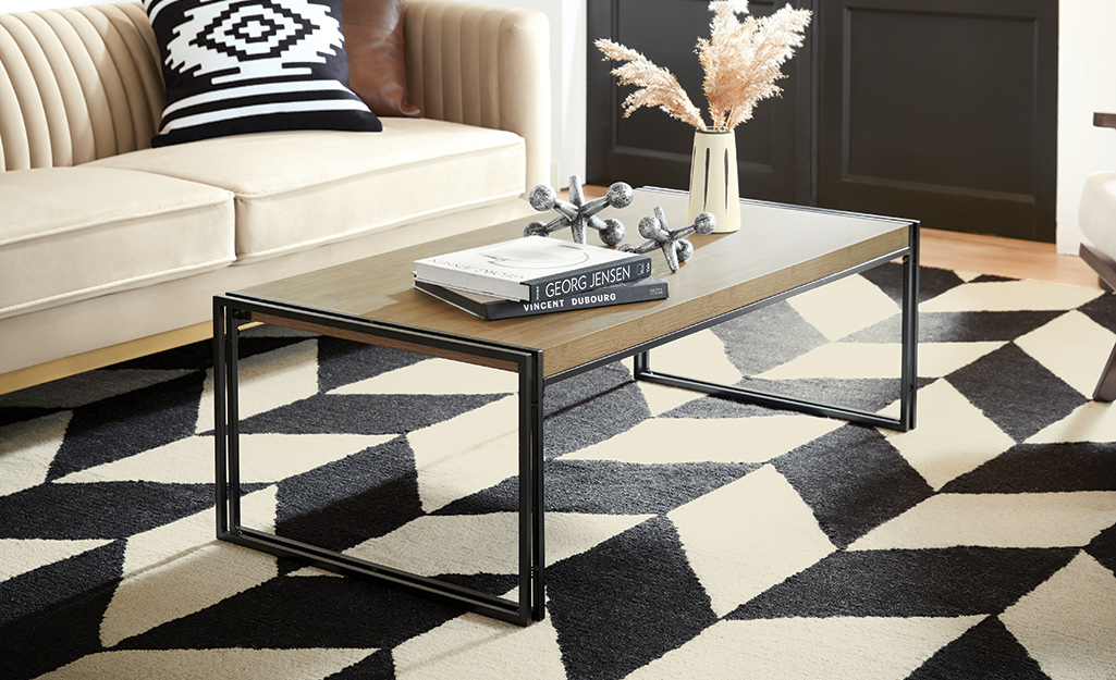 A rug with a black and white geometric pattern lays under a coffee table and in front of a couch.