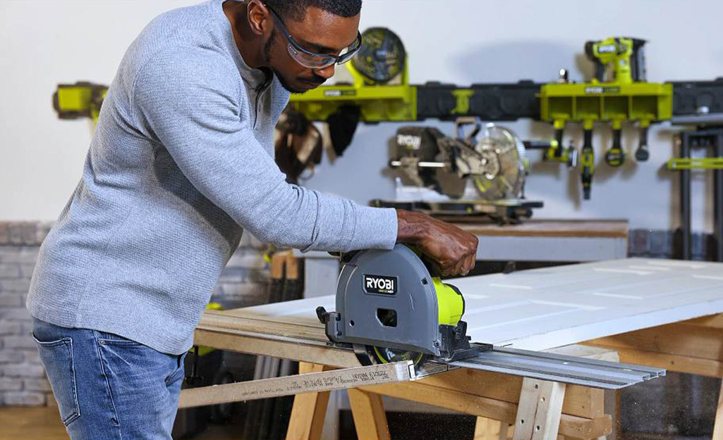 A person cutting a board with a circular saw.