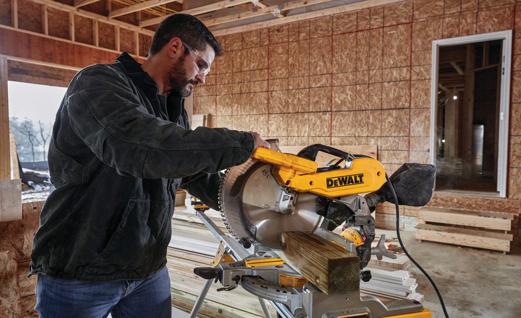 A person using a miter saw to cut an angle.