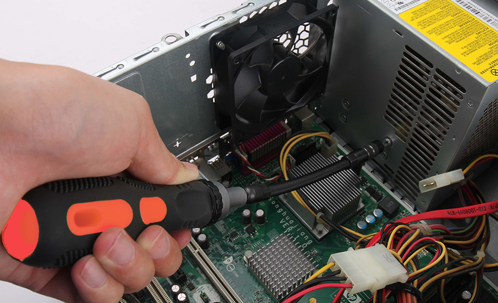 A person uses a screwdriver on a computer hard drive.