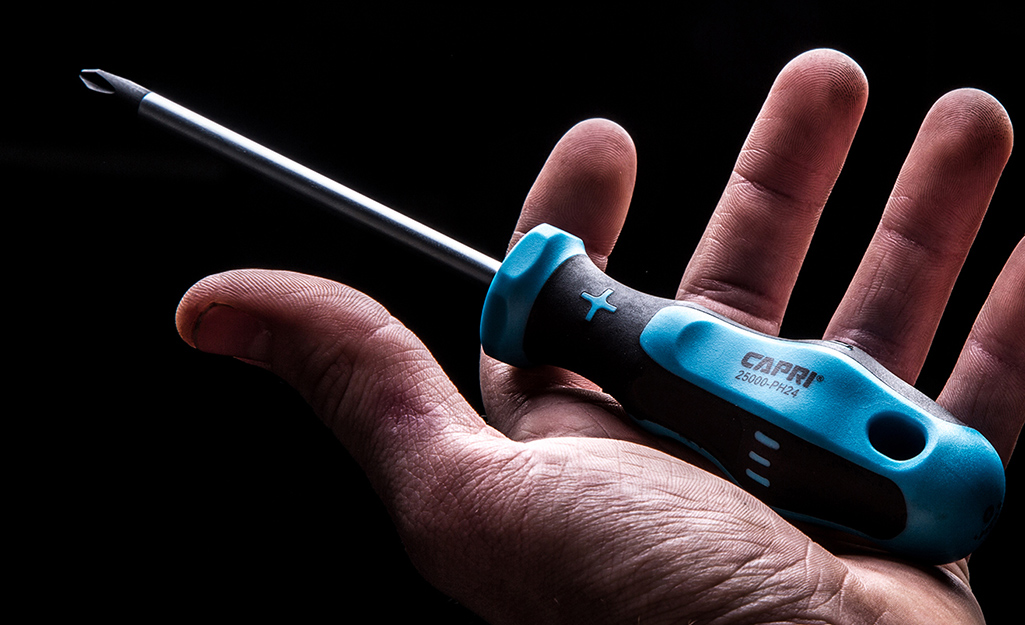 A person holds a Phillips head screwdriver.