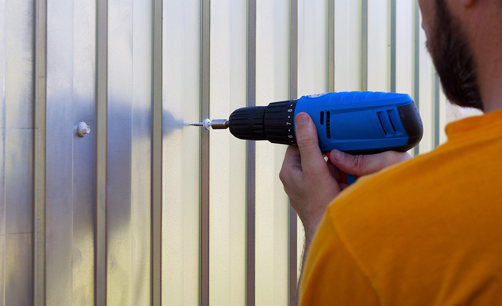 A person driving a screw into sheet metal.