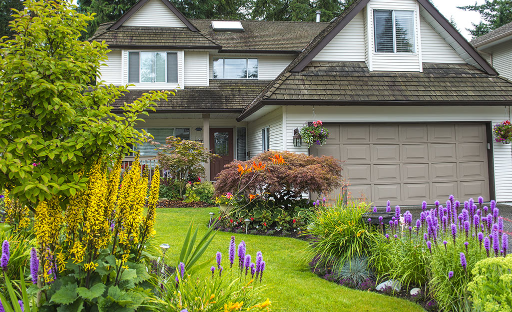 A vibrant green front lawn with neatly landscaped areas of flowers.