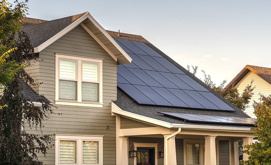 Solar panels cover the sloped roof above the front porch of a two-story house. 