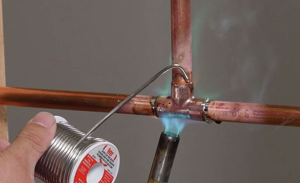 A person holds wire while soldering.