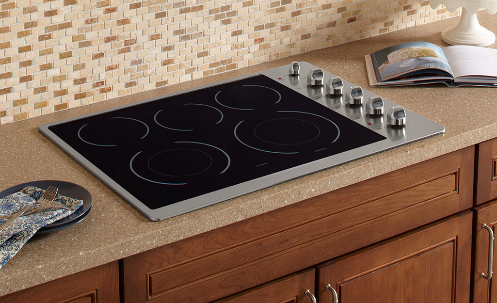 A five-burner electric stovetop with a smooth surface installed in a kitchen countertop.