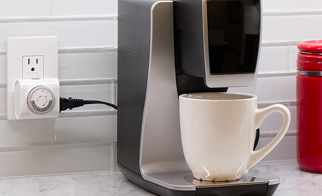 An electric coffee machine plugged into a timer.