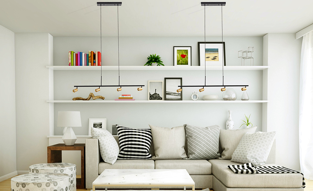 Track suspension kits hang track lighting low over a couch in a living room.