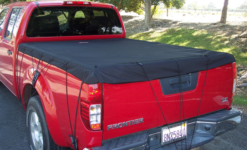 A closeup of a red pickup truck with a black cover