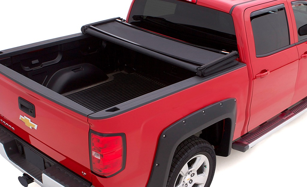 A red pickup truck with a tri-fold truck bed cover