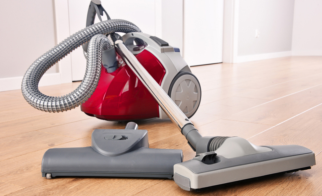 A canister vacuum atop hardwood floors.